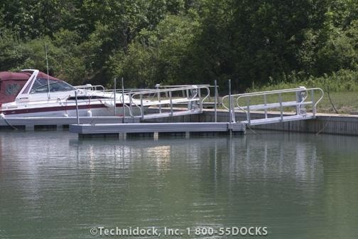 TechniDock aluminum composite floating dock with pontoon boats moored on calm wooded lake