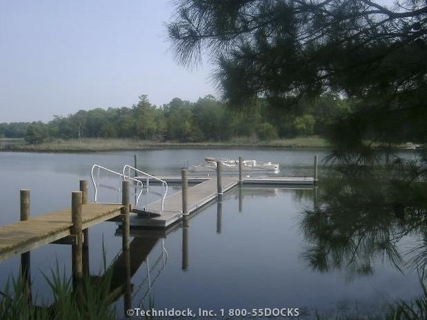 TechniDock aluminum composite floating dock with boat slips on calm wooded lake