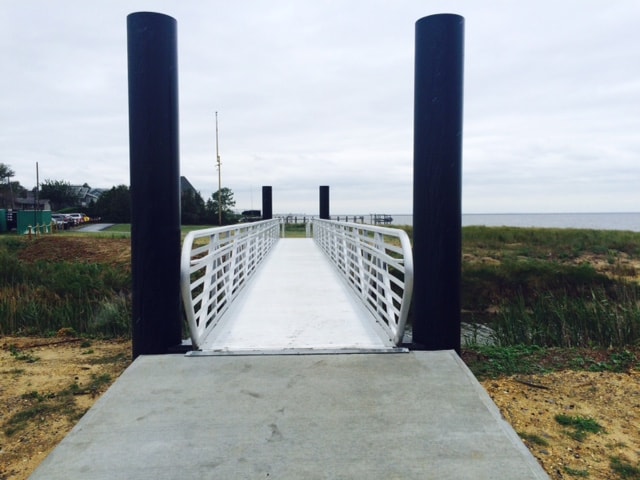 TechniDock ADA aluminum gangway with white railings leading to waterfront ferry terminal