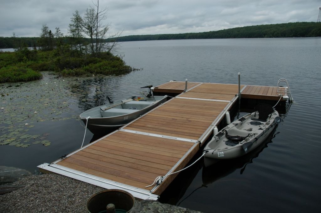TechniDock aluminum floating dock with wood decking and boats on a calm lake